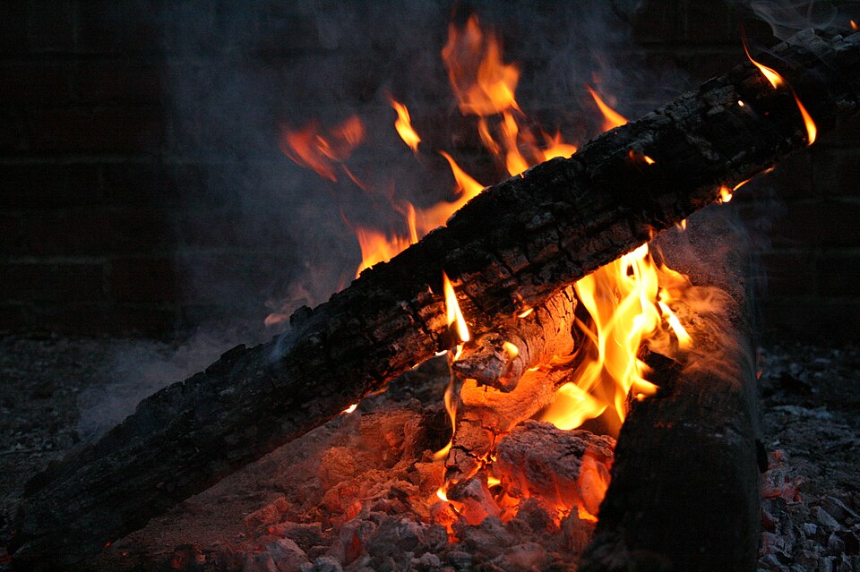 A bed of coals under ash — what a banked fire looks like when it is uncovered in the morning.