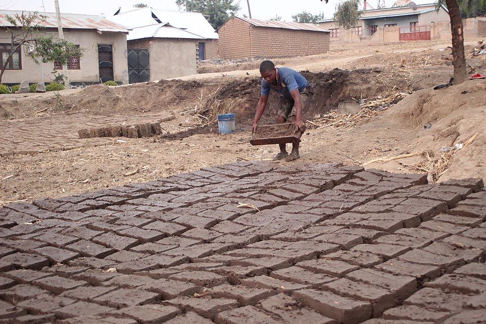 Moulding mud blocks: the bottomless mould is filled on the ground, struck off and lifted straight up, and the blocks are left in rows to dry. Walls are laid only once they are dry right through.