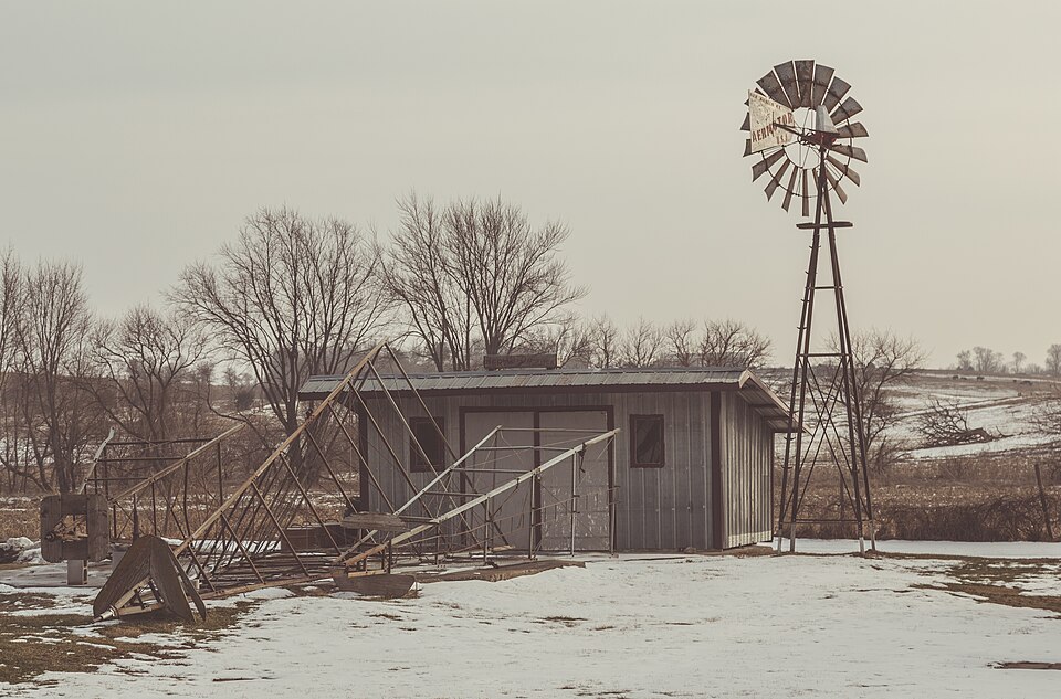 A multi-blade farm wind pump: many narrow blades give high torque in a light wind, driving a rod down the tower to a pump at the bottom. It turns itself into wind and furls itself in a gale.