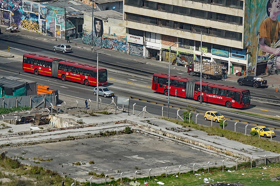 Articulated TransMilenio buses on dedicated lanes in Bogotá, Colombia (2018): bus rapid transit on an arterial, separated from the general traffic beside it.