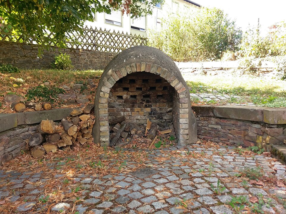 A reconstructed updraught kiln standing open: firebox below, perforated floor carrying the ware above.