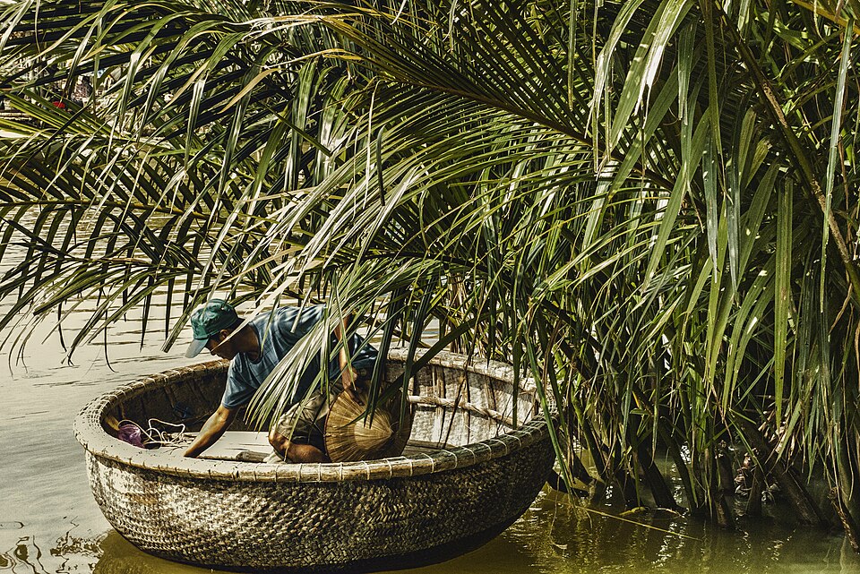 A woven bamboo basket boat among palms: the tight weave is the hull, sealed on the outside.