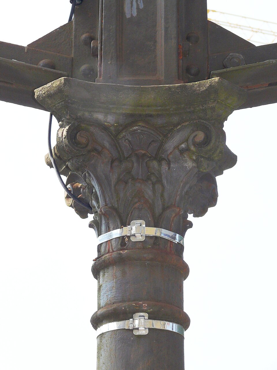 A cast-iron column at Immenstadt station, Germany (2025): riveted iron beams bear on its capital, and the column carries their load straight down in compression.