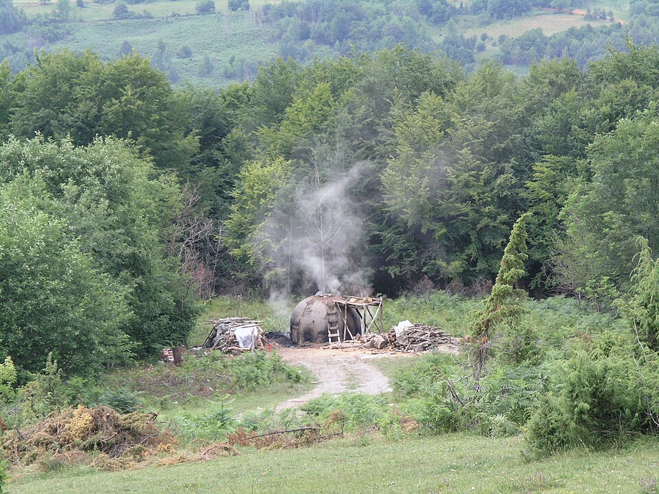 An earthed charcoal clamp burning in a forest clearing, Bjelasica, Montenegro.