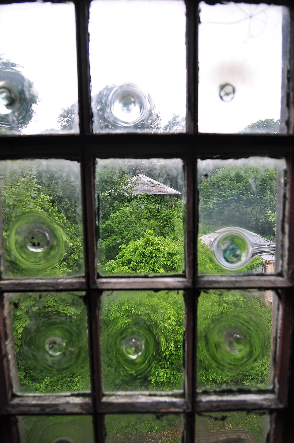 Small panes of early crown glass held in wooden glazing bars. Hand-made glass came only in small sheets, which is why old windows are divided into many panes.