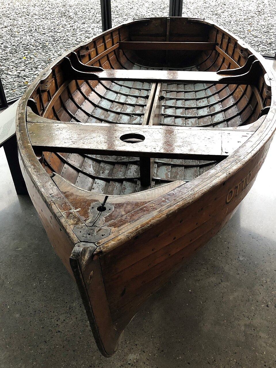 A clinker-built dinghy from above: bent frames inside the lapped planks, thwarts across, and a transom at the stern.