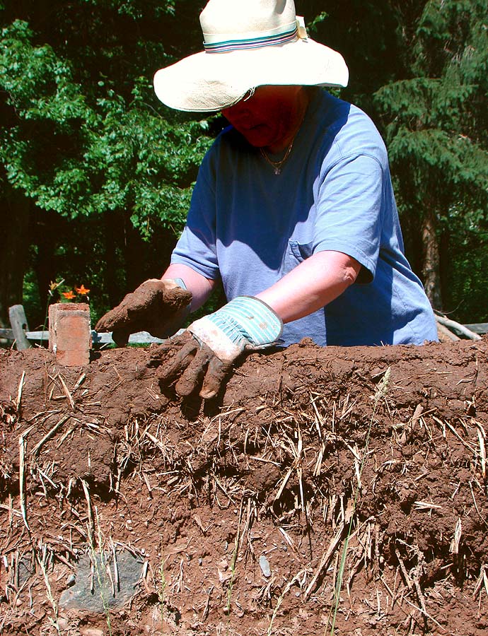 Building a cob wall by hand: subsoil, straw and water, laid in lifts.