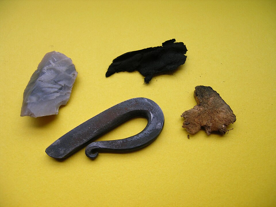 A flint-and-steel kit: flint, steel striker, char cloth and amadou. The steel will not light raw tinder — it needs a charred catcher.