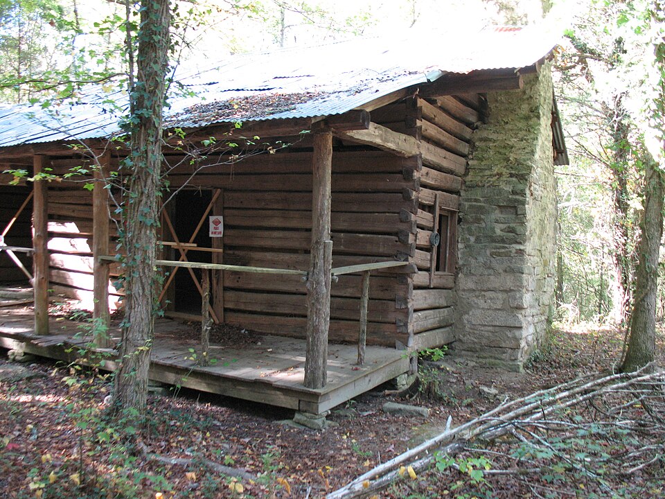 A log cabin with its chimney built of stone outside the gable wall, so the fire never touches the logs.