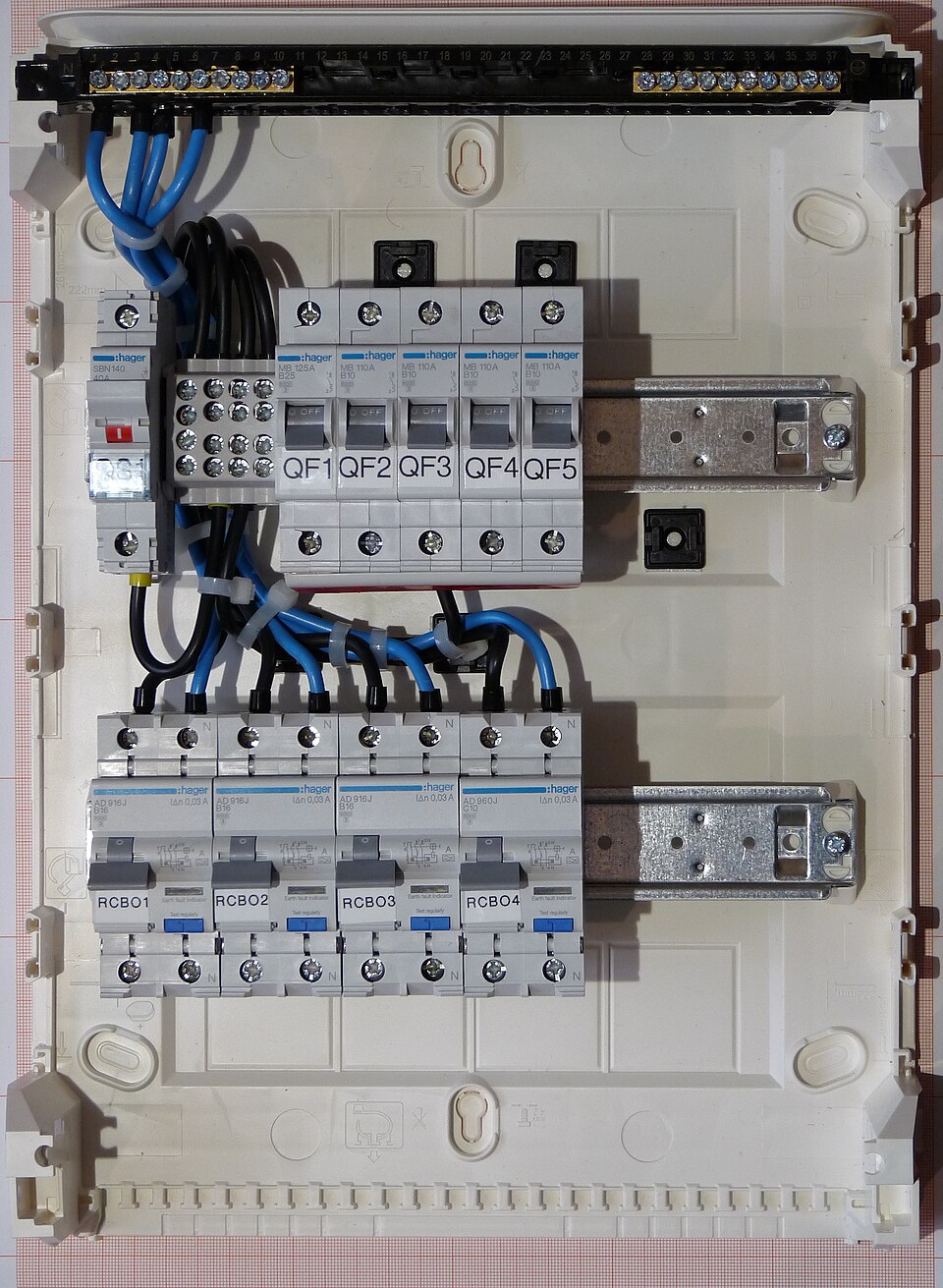 A small distribution board: miniature circuit breakers and combined RCD-breakers (RCBOs) on a rail, one per circuit. Each breaker protects its cable from overload and short circuit; the residual-current element protects people.