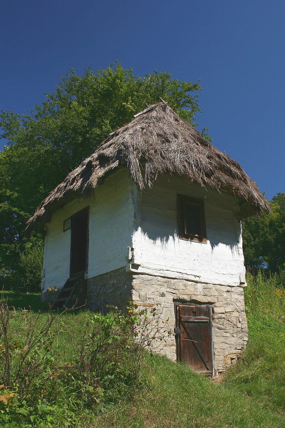 A stone cellar cut into a slope with the store below and living space above, Humenné open-air museum.