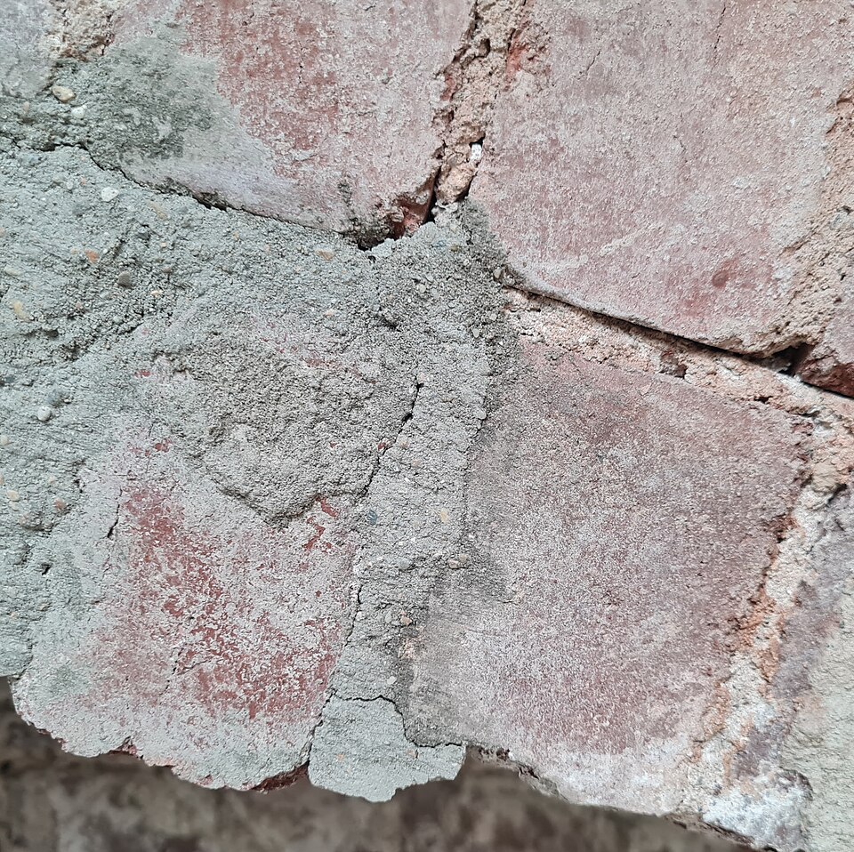 Lime mortar in an old brick wall: softer and more porous than the bricks, so movement and moisture work through the joint rather than the masonry.