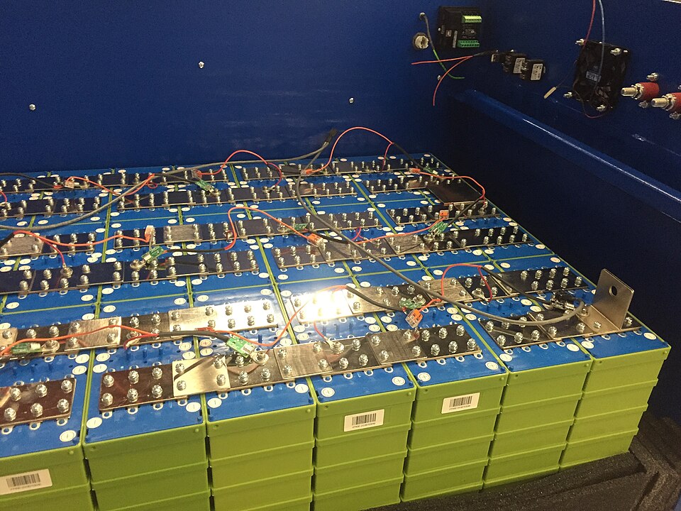 A large battery bank of lithium iron phosphate cells — about 3.2 V each — connected in series with busbars. The thin wires run to a battery management system that watches every cell's voltage.