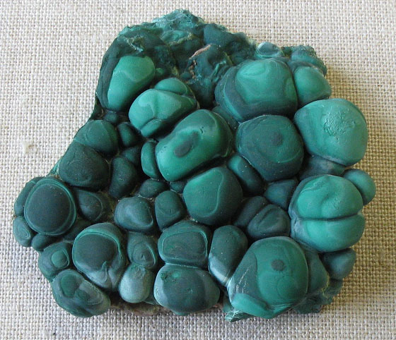 Malachite, a copper carbonate: rounded green masses with darker bands inside. Green or blue stains and crusts on rock are the sign of copper, and this is the ore the first smelters used.