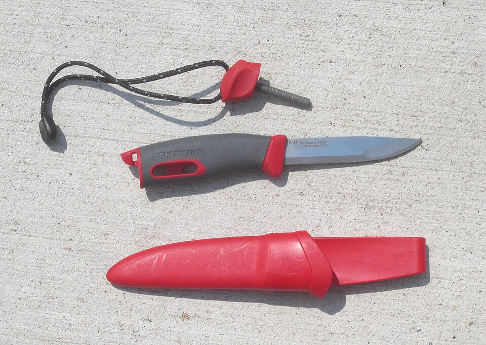 A ferrocerium rod and a knife with a square spine to strike it. Sparks leave the rod at roughly 3,000 °C, it works soaked, and it lasts for thousands of strikes — the single highest-value fire item to carry.
