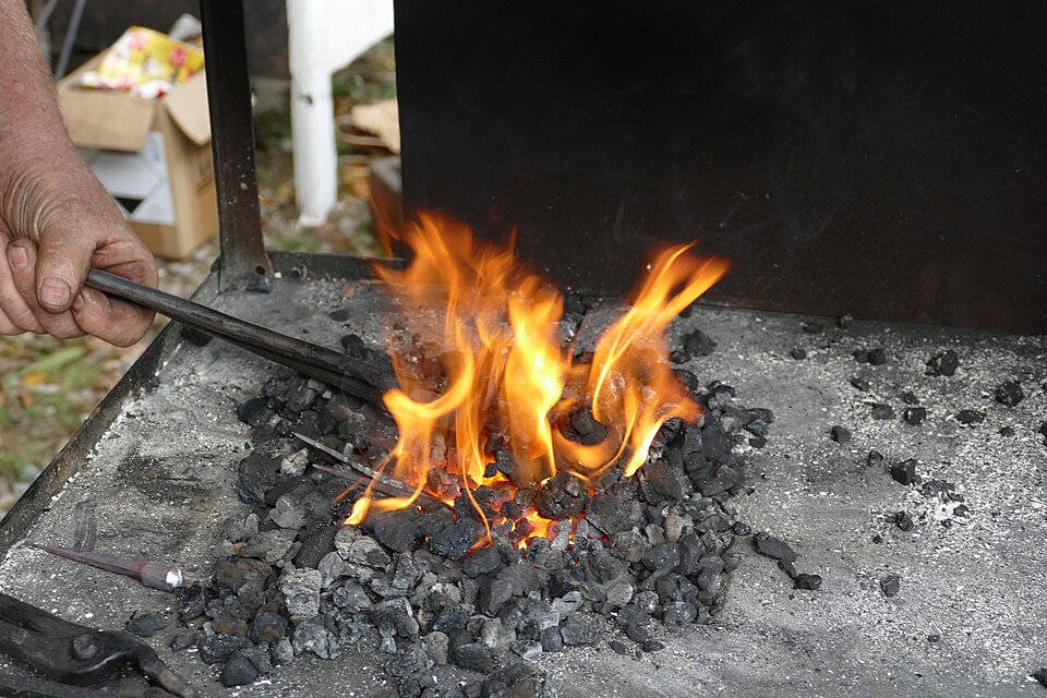 A forge fire in use: a small, deep heart of burning fuel, not a spread bed.