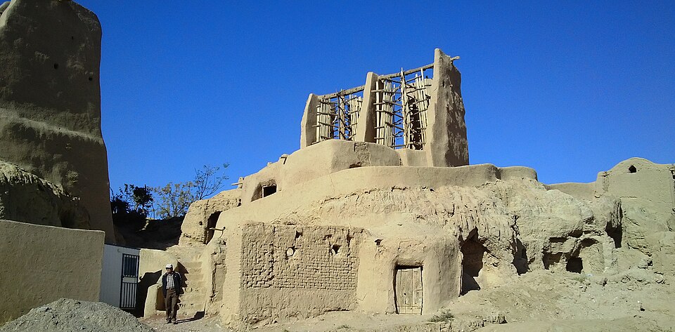 The vertical-axis mills at Nashtifan, Iran. Walls funnel a wind that blows from one quarter for months onto rotors turning a vertical shaft straight down to the stones — no gearing anywhere in the machine.