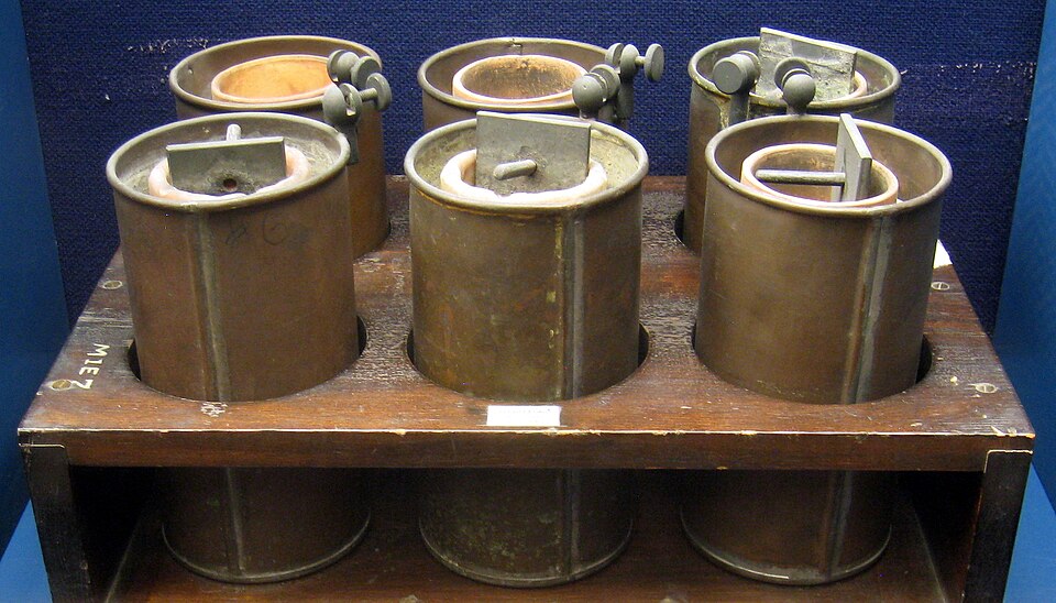 Daniell cells of the kind built from 1836 (Smithsonian): each copper can holds copper sulphate solution and an unglazed clay pot, and the pot holds the zinc in its own solution. The porous pot is what keeps the two liquids apart.