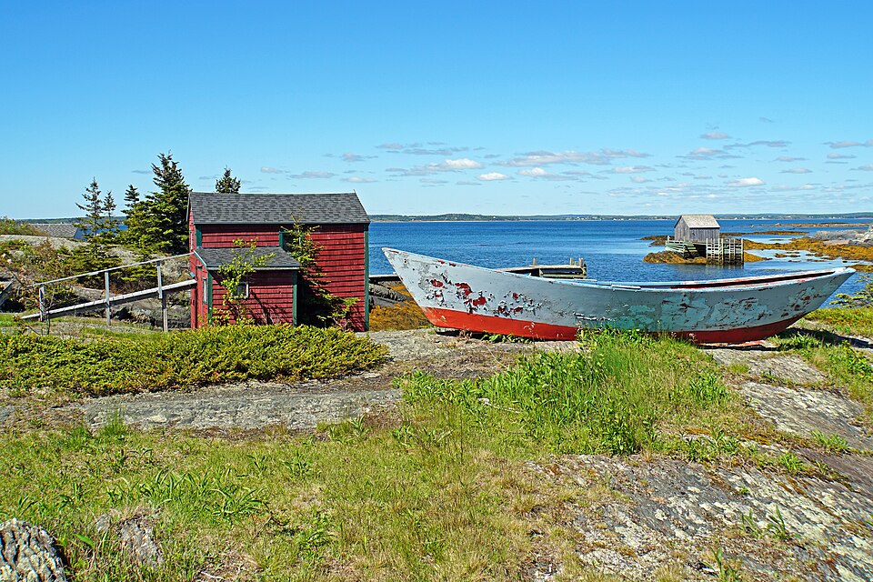 A flat-bottomed dory hauled out above the water in Nova Scotia, 2016: flared plank sides on a narrow flat bottom.