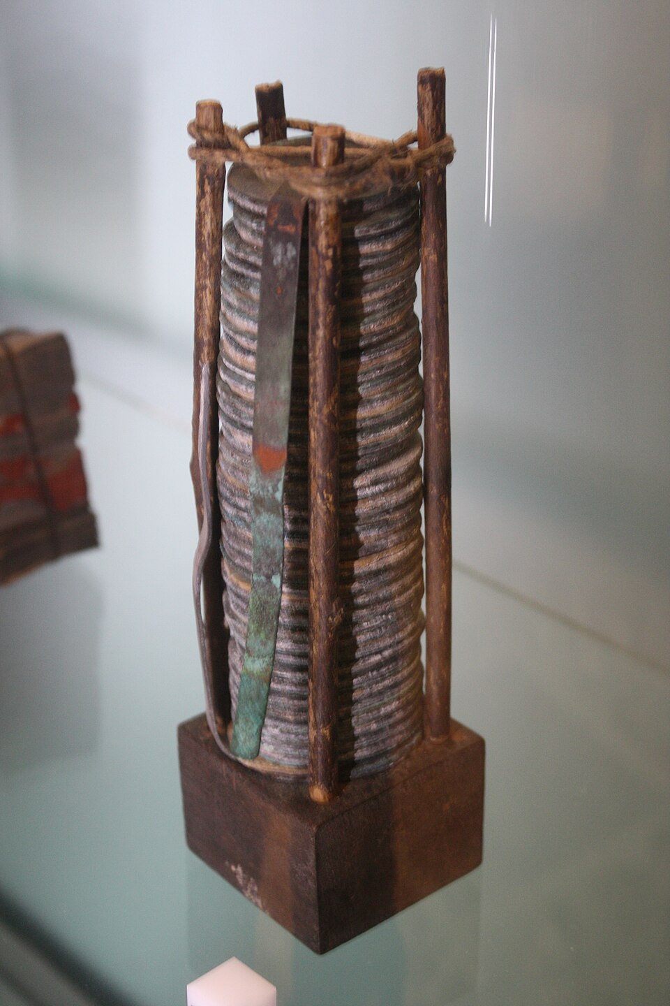 A voltaic pile in the Tempio Voltiano, Como: a stack of alternating zinc and copper discs with brine-soaked separators, held in a wooden frame, with a copper strip leading off each end.