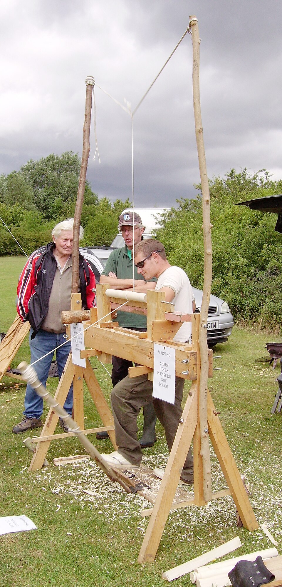 A pole lathe: springy pole, cord, treadle. The first machine that shapes a part rather than a tool.
