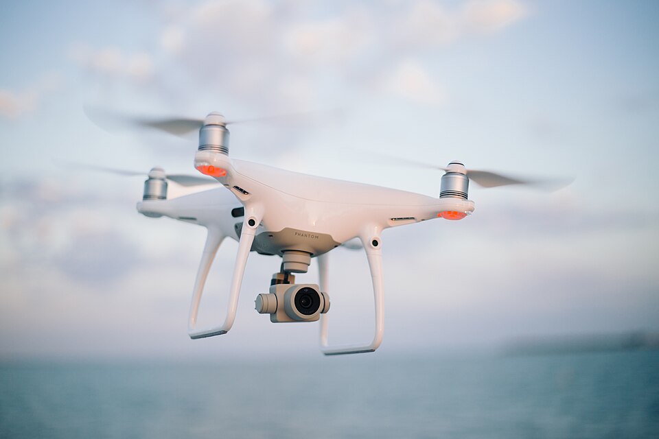 A four-rotor camera drone in flight, 2018.
