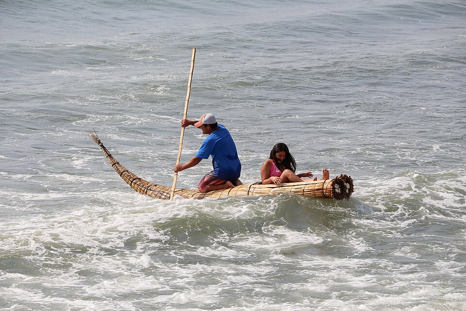 A reed-bundle boat (caballito de totora) paddled out through the surf at Huanchaco, Peru, 2014.