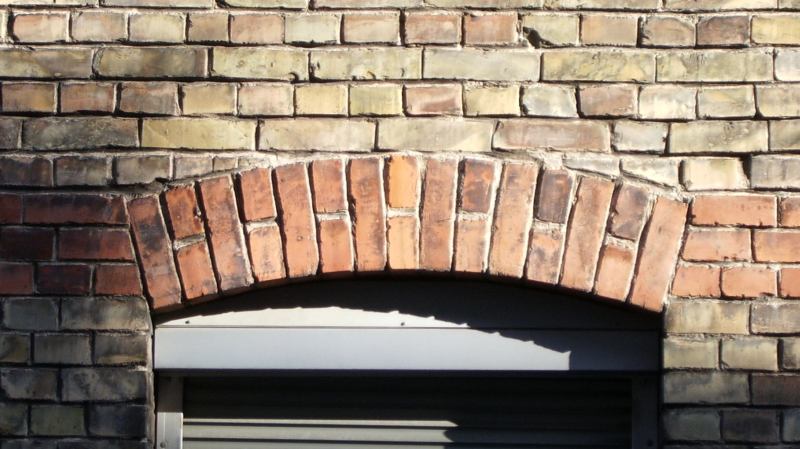 A segmental brick arch over a window. The bricks stand on edge and radiate from one centre, so the load above is carried out to the sides in compression.