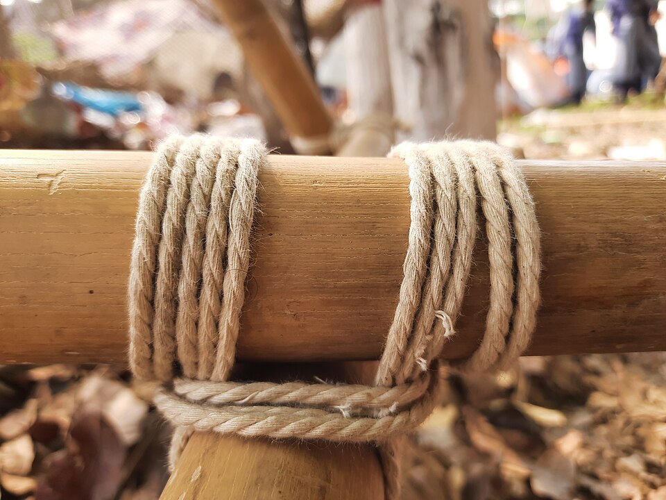 A square lashing binding two poles at right angles: wrapping turns, then frapping turns between the poles to cinch them tight.