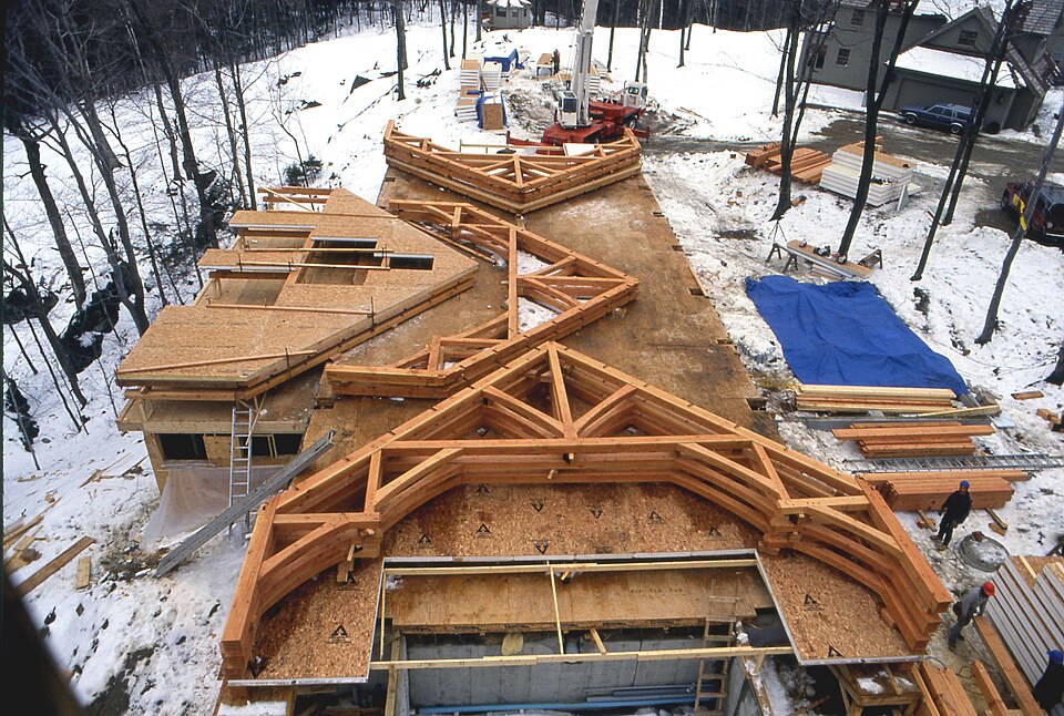 Timber-frame bents cut, joined and test-fitted on the ground before raising. Each bent is one cross-section of the building, braced so it cannot rack.