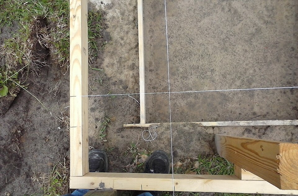 Two string lines crossing over the corner of a foundation: the crossing is the corner, found again at any time.