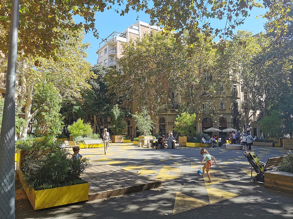 A superblock street in Sant Antoni, Barcelona (2023): through traffic removed, the carriageway turned into a square with trees, seats and room for children to play.