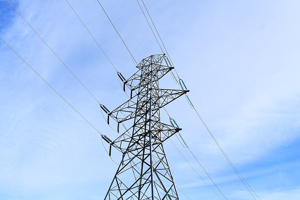 A steel lattice transmission tower in Alberta. Height and long insulator strings keep conductors at tens to hundreds of thousands of volts clear of the ground, the tower and people.