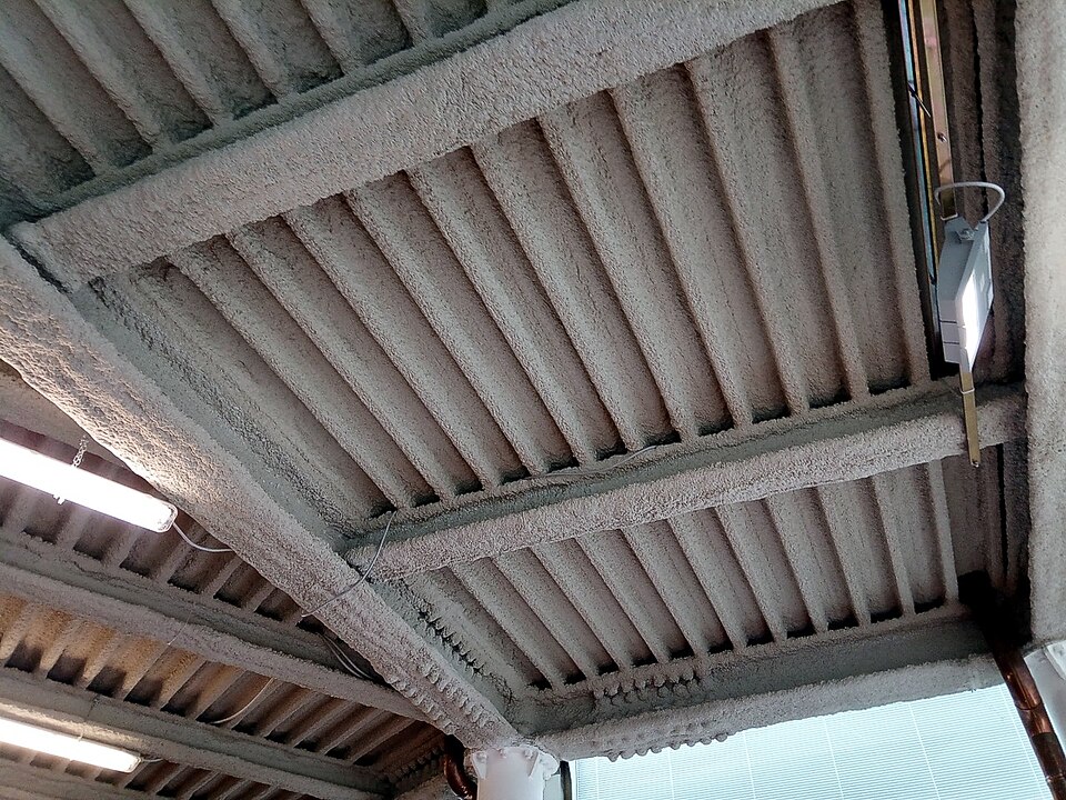 Steel roof beams coated with sprayed fire protection (2018), which keeps the steel below the temperature at which it loses its strength.
