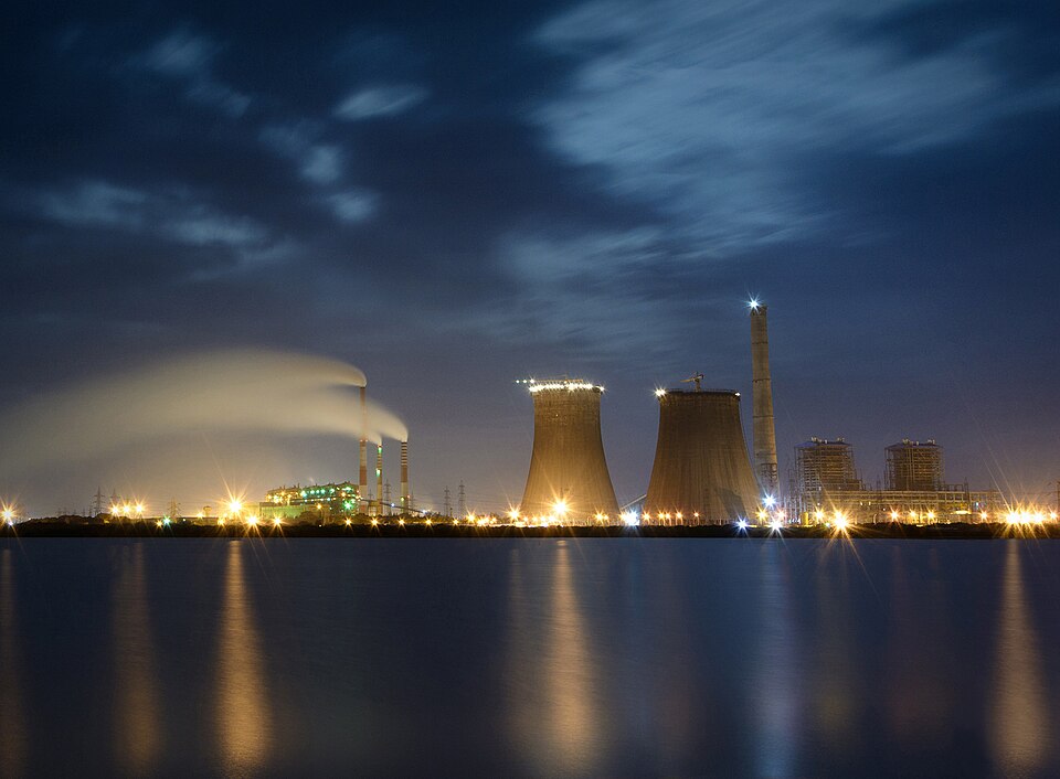 Tuticorin coal-fired power station, India, at night. Coal raises steam, steam spins turbines and generators, and the cooling towers and stack reject the heat that could not become electricity — usually more than half of it.