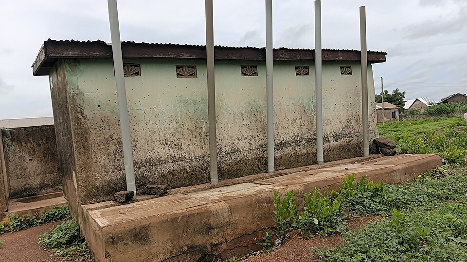 A block of VIP latrines with a vent pipe per pit run up the outside wall, above the roof line.