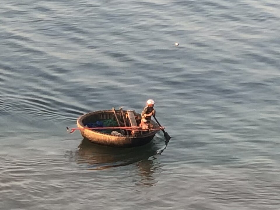 A round basket boat off the coast of Vietnam, 2019, worked by one person with a single paddle.