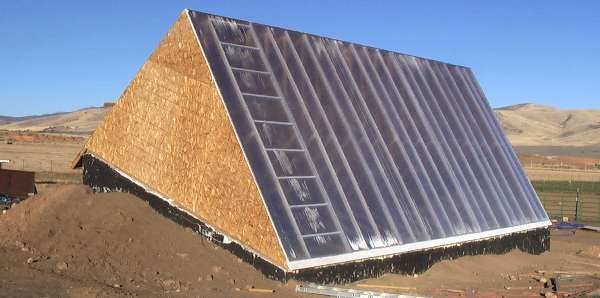 A walipini (pit greenhouse), 6 × 12 m, in Utah: sunk into the ground, earth banked against its walls, and a steep glazed roof facing the winter sun.