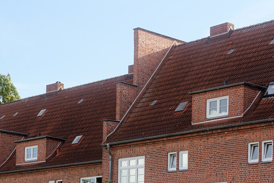 Brick terraces at Am Salzhaff, Wismar, Germany (2018): the party walls rise through the tiled roofs as parapets, so fire in one roof space cannot run along the row.
