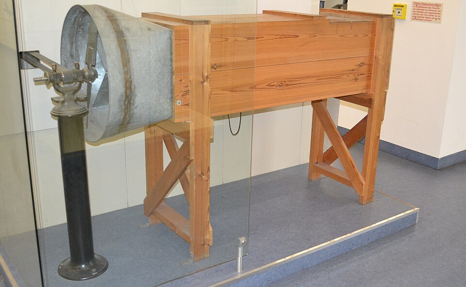 A replica of the Wrights' 1901 wind tunnel: a long wooden box on trestles with a metal funnel at one end.
